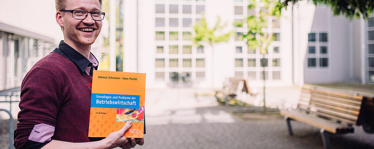 Bild Dozent Dr. Daniel Hunold mit dem Buch "Grundlagen und Probleme der Betriebswirtschaft"